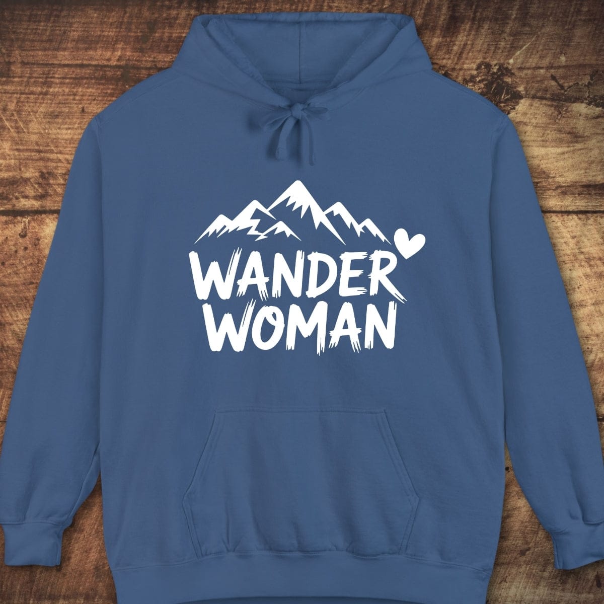 Wander Woman Comfort Colors Hoodie with mountain graphic and text, laid flat. Features a soft, garment-dyed unisex fit, perfect for outdoor adventures.