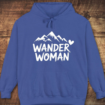 Wander Woman Comfort Colors Hoodie with mountain graphic, heart, and slogan on front. Features kangaroo pocket, drawstring hood, relaxed unisex fit, laid on wooden surface.