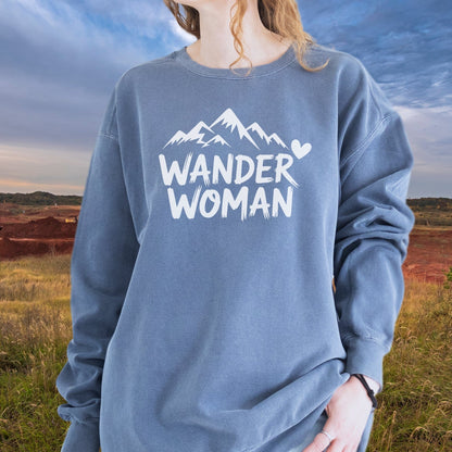 Woman outdoors wearing a slate-blue Wander Woman Sweatshirt with mountain graphic, showcasing its relaxed fit and luxurious, garment-dyed fabric.
