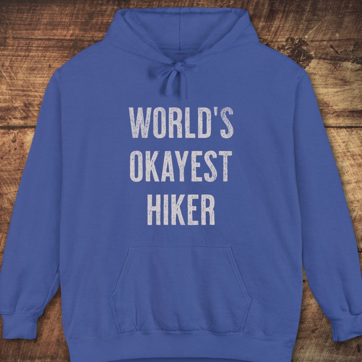 World's Okayest Hiker Comfort Colors Hoodie, featuring distressed white text, jersey-lined hood, front pouch pocket, and relaxed unisex fit, ideal for outdoor adventures.