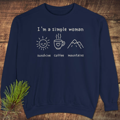 I'm A Simple Woman Comfort Colors 1566 Sweatshirt featuring sunshine, coffee, mountains icons on navy-blue, displayed on wood with a pine sprig.