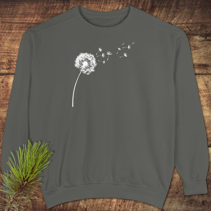 Dandelion Comfort Colors Sweatshirt with a dandelion print on charcoal-gray fabric, showcased on wood. Features relaxed fit and premium, garment-dyed material.