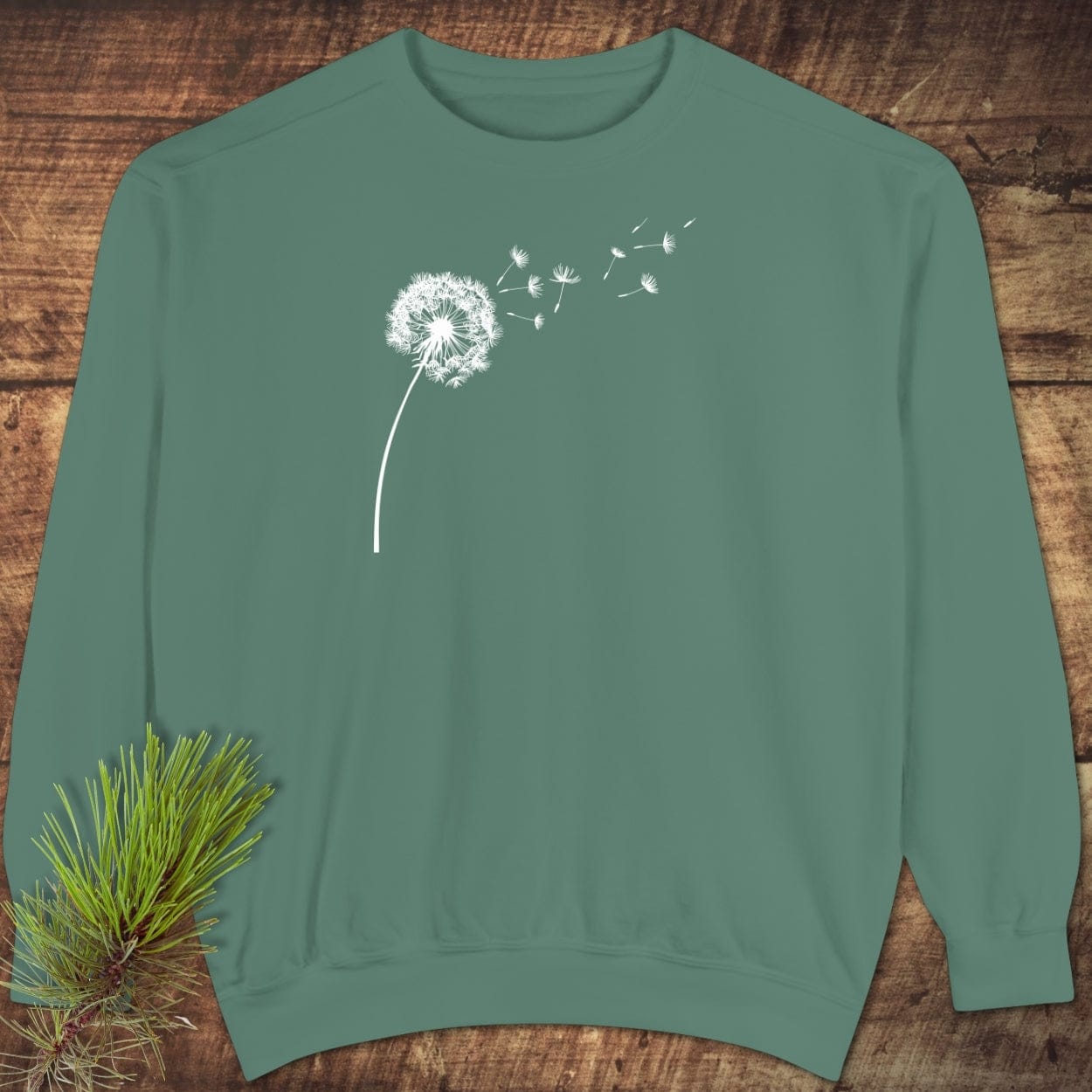 Dandelion Comfort Colors Sweatshirt displayed on wood, showcasing a white dandelion design, highlighting its relaxed fit and premium, ring-spun cotton-polyester blend.