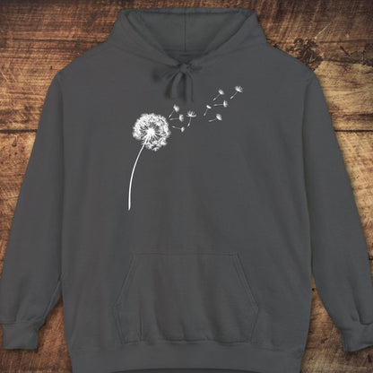 Dandelion Comfort Colors Hoodie, featuring a white dandelion graphic, front pouch pocket, and drawstring hood, laid on a wood-grain surface for a cozy, relaxed fit.