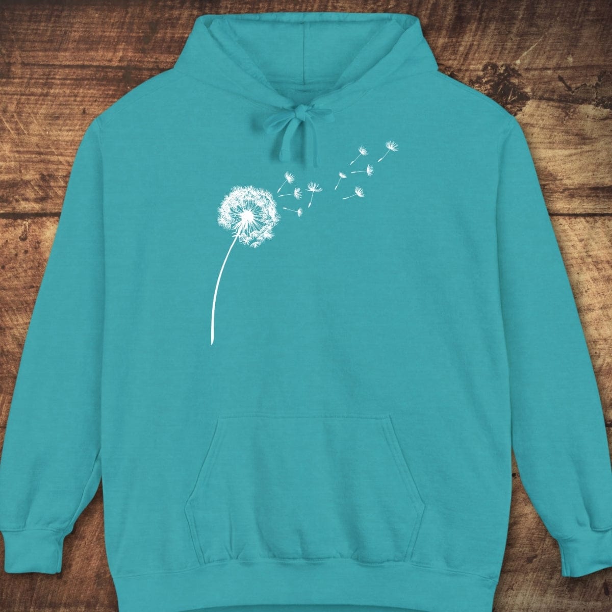 Dandelion Comfort Colors Hoodie with a dandelion silhouette, kangaroo pocket, and drawstrings, laid flat. Garment-dyed for a relaxed, vintage look.