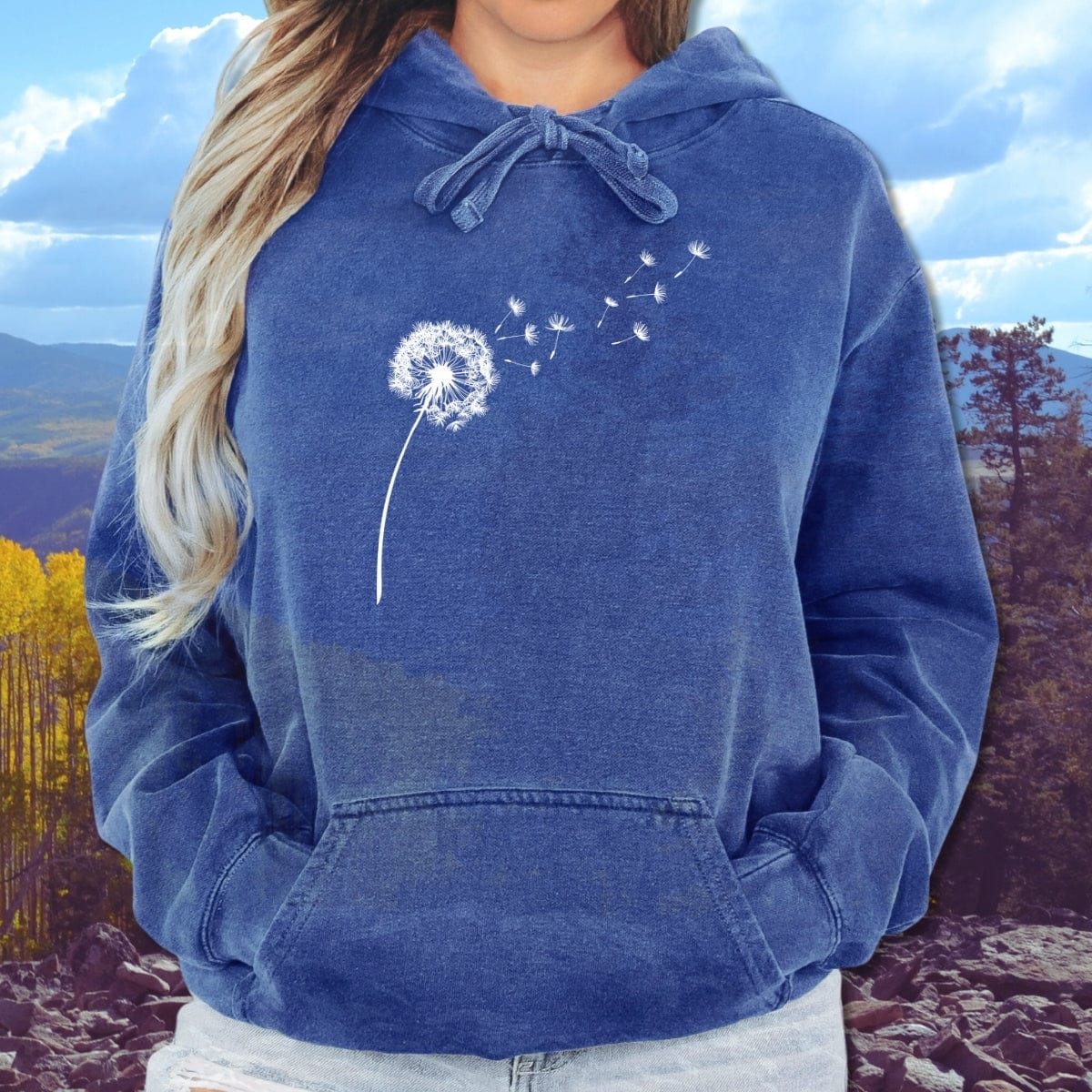 Person wearing a Dandelion Comfort Colors Hoodie with a white line-art dandelion design, hands in kangaroo pocket, showcasing its relaxed fit and cozy fleece material.