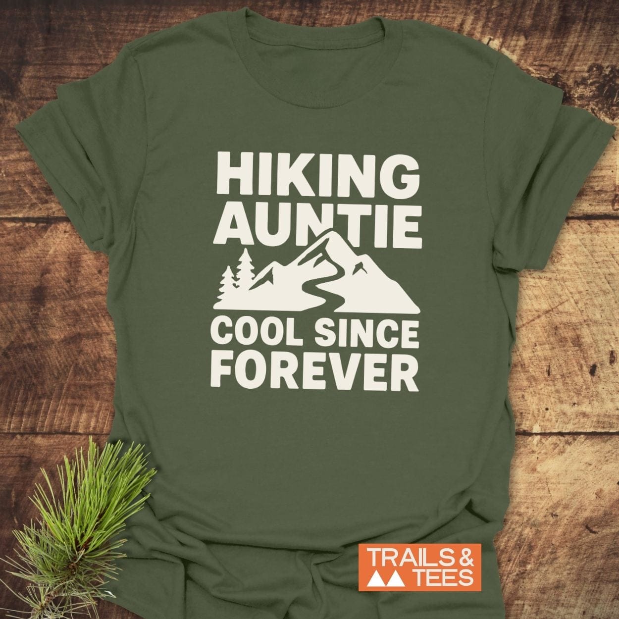 Hiking Auntie T-Shirt featuring a mountain graphic and slogan in white on an army-green tee, crafted from soft ring-spun cotton by Trails & Tees.