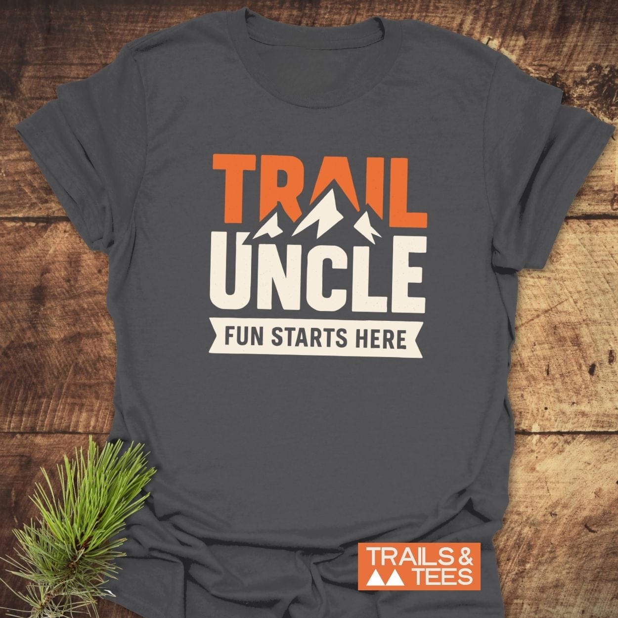 Trail Uncle Funny T-Shirt in dark gray, featuring an orange and off-white mountain design with the phrase FUN STARTS HERE, styled with a pine sprig.