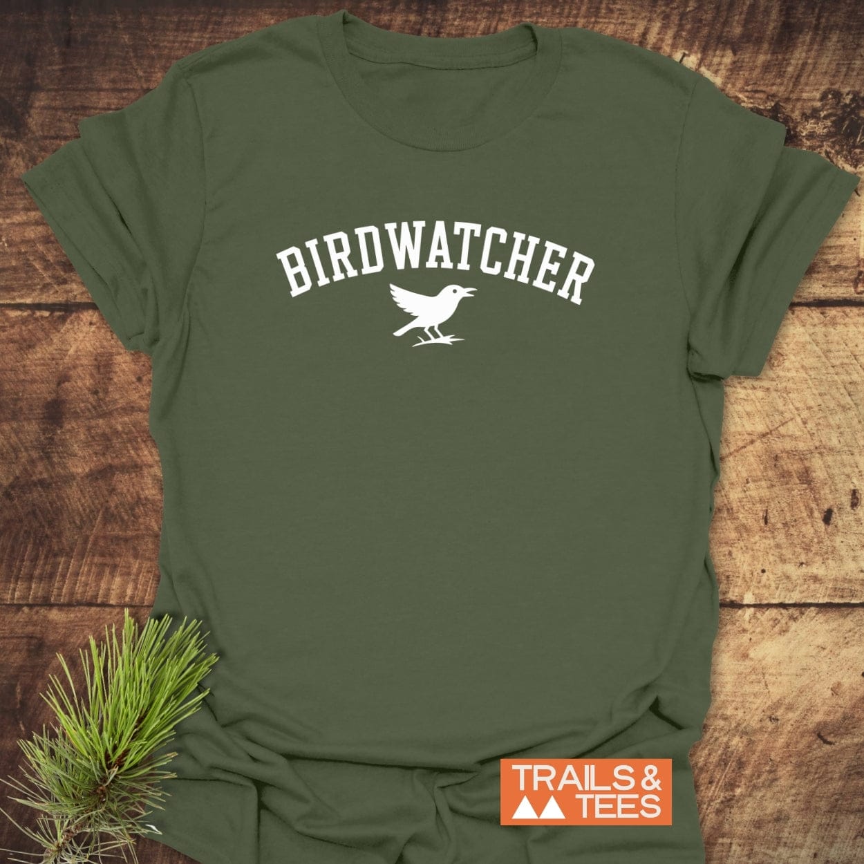Birdwatcher Varsity T-Shirt featuring BIRDWATCHER print and bird silhouette, on soft cotton. Includes TRAILS & TEES logo, emphasizing outdoor adventure.