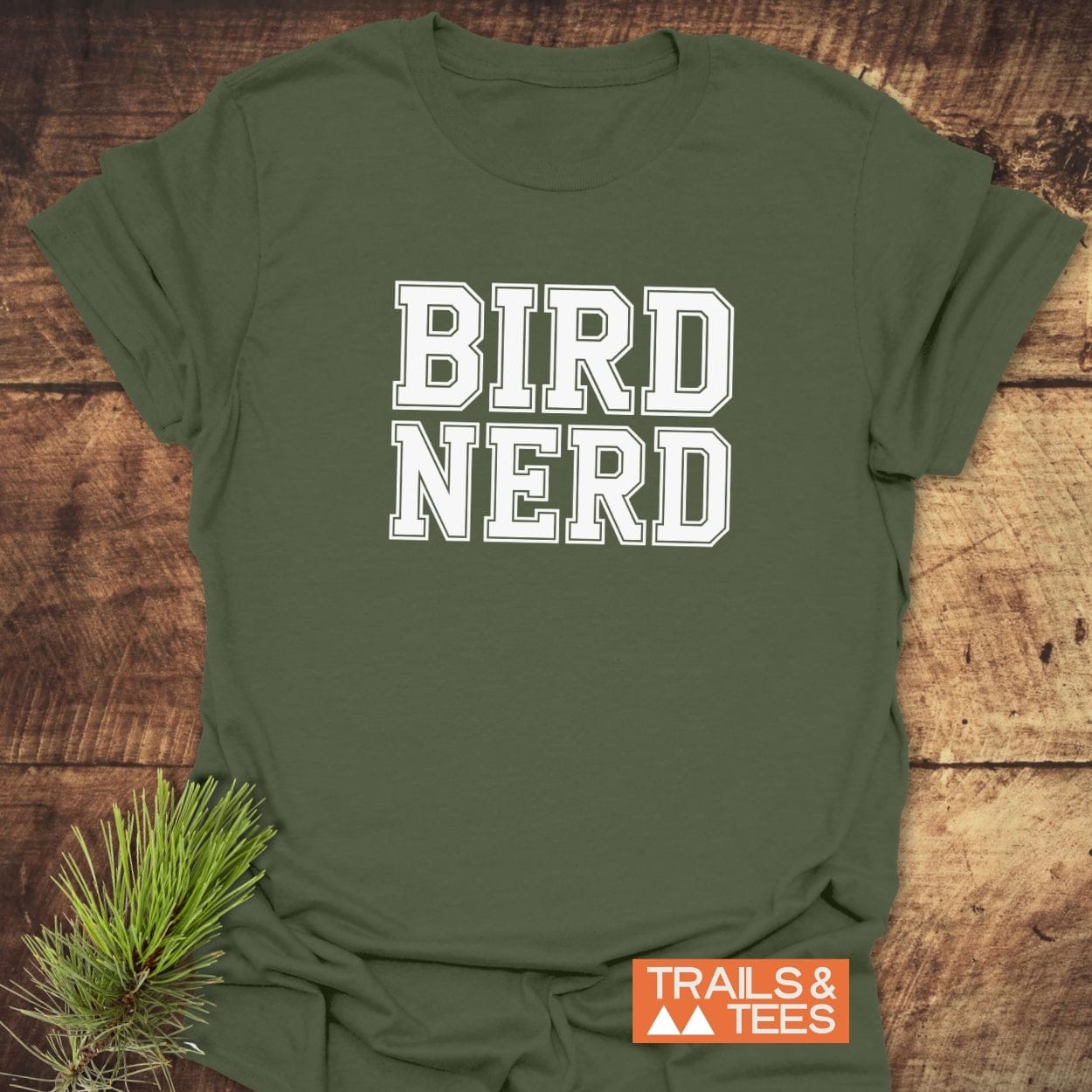 Bird Nerd Varsity T-Shirt on rustic wood, featuring white varsity letters. Soft, lightweight ring-spun cotton for everyday adventure. Includes orange Trails & Tees logo.