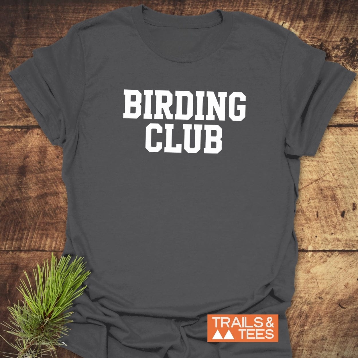 Heather-gray Birding Club T-Shirt with white collegiate letters, laid flat on wood, featuring comfort-focused design in soft cotton, durable print, and eco-conscious production.