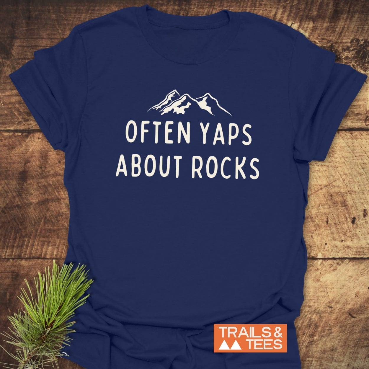 Often Yaps About Rocks T-Shirt with mountain silhouette and slogan, featuring durable prints on soft, ring-spun cotton, designed for outdoor enthusiasts.