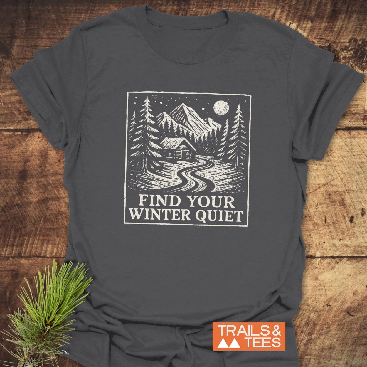 Find Your Winter Quiet Cabin T-Shirt featuring a snowy mountain scene graphic with slogan. Made from soft ring-spun cotton, designed for outdoor enthusiasts.