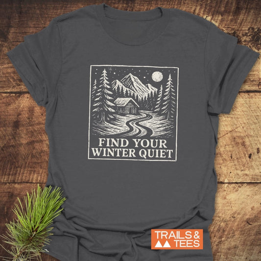 Find Your Winter Quiet Cabin T-Shirt featuring a snowy mountain scene graphic with slogan. Made from soft ring-spun cotton, designed for outdoor enthusiasts.