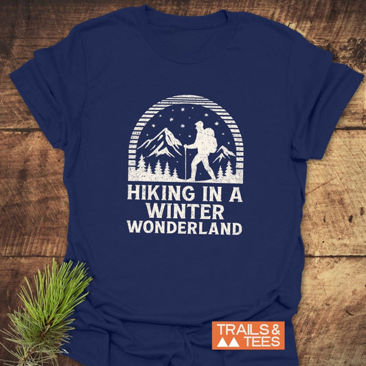 Hiking In A Winter Wonderland T-Shirt with a winter scene print, crafted from soft cotton for comfort, featuring “TRAILS & TEES” logo, ideal for outdoor enthusiasts.