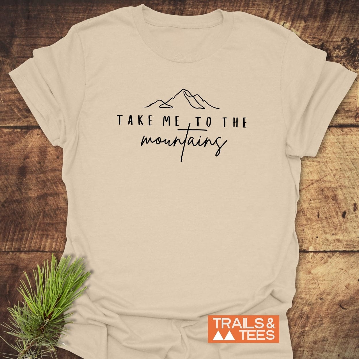 Take Me To The Mountains Minimal T-Shirt: Light-beige, features mountain line-drawing, text, crafted from soft ring-spun cotton. Includes durable prints, taped shoulders, no side seams.