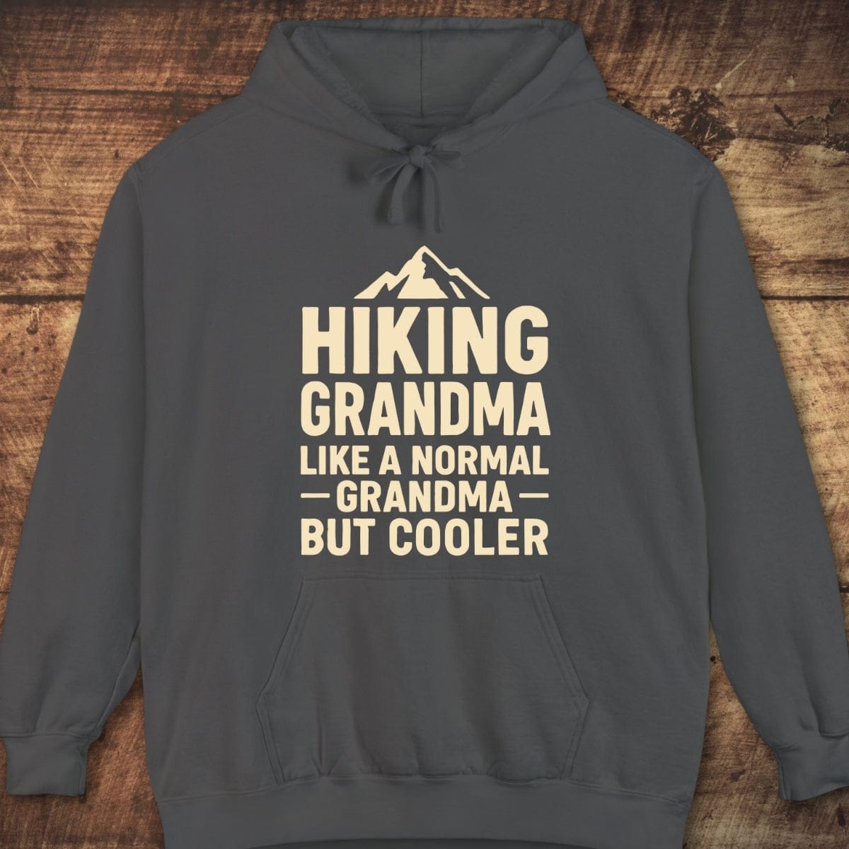 Charcoal-gray hoodie with HIKING GRANDMA text and mountain icon, featuring a kangaroo pocket and jersey-lined hood. Ideal for layering, offering a relaxed, cozy fit.