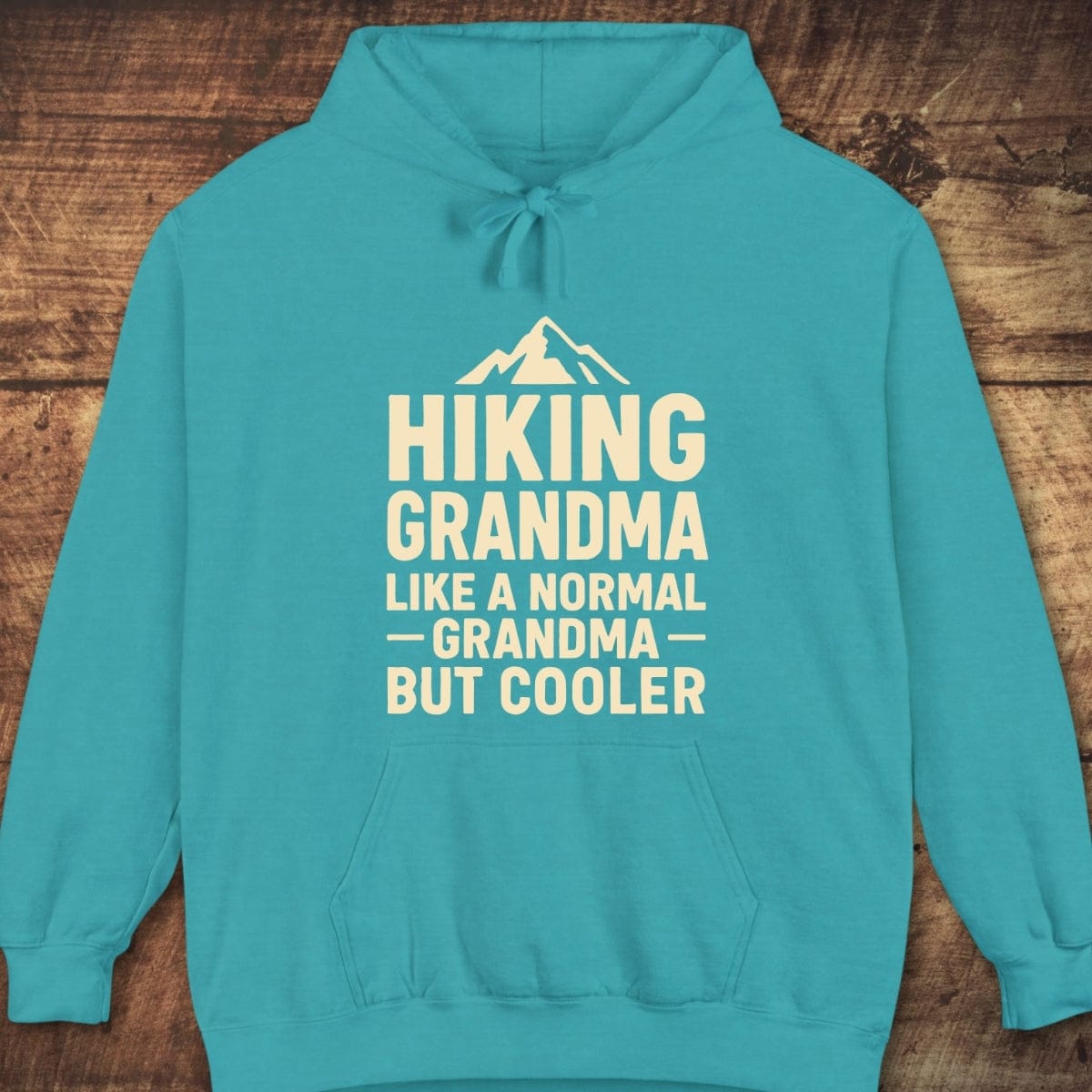 Hiking Grandma Comfort Colors Hoodie with mountain graphic and text. Features drawstring hood, kangaroo pocket, ribbed cuffs, garment-dyed for a vintage feel.