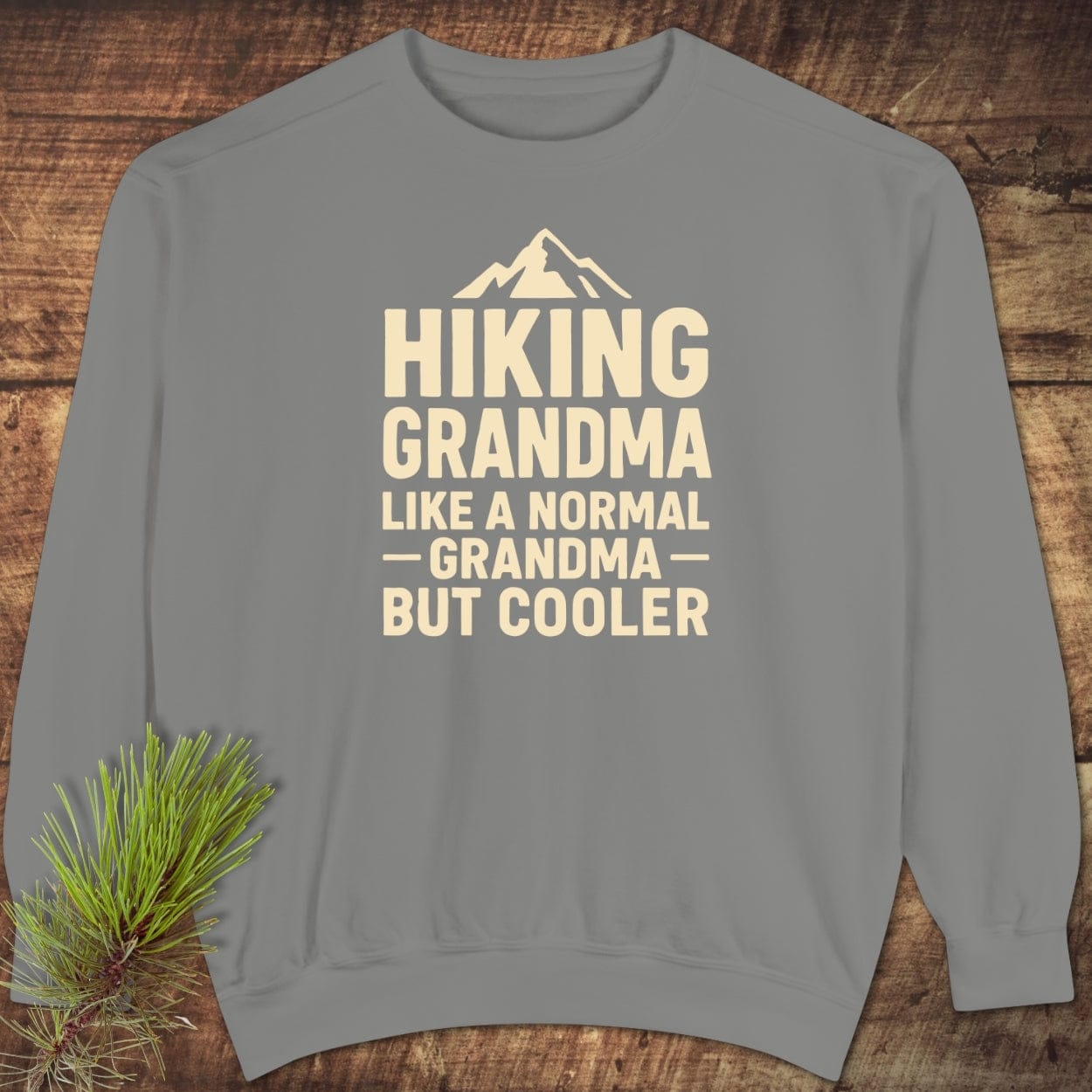 Hiking Grandma Comfort Colors Sweatshirt on rustic wood, featuring a mountain icon and playful text. Made of cozy, durable ring-spun cotton blend.