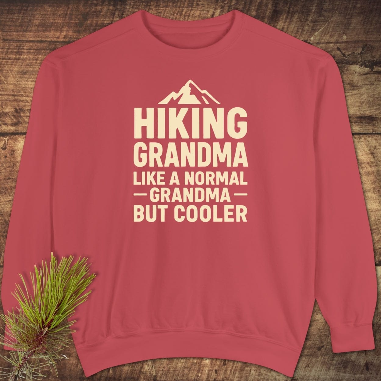 Hiking Grandma Comfort Colors Sweatshirt featuring a mountain icon and playful text, showcasing its relaxed fit and quality material on a wooden surface.