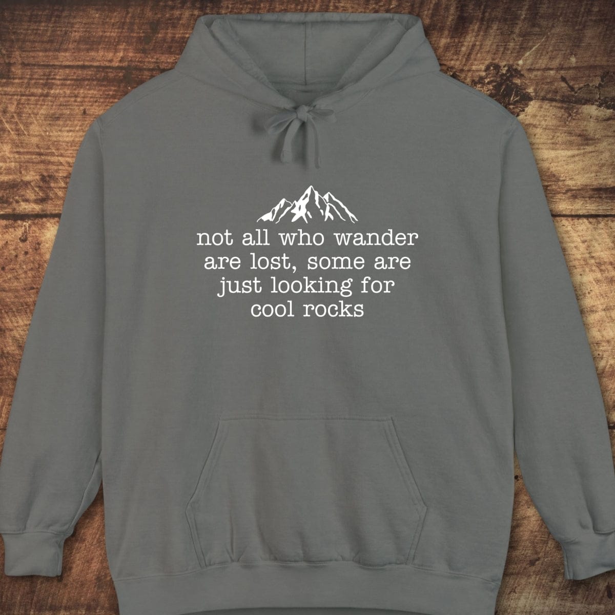 Looking For Cool Rocks Comfort Colors Hoodie with a white mountain graphic and quote, displayed on wood. Soft, unisex fit perfect for layering and adventure.