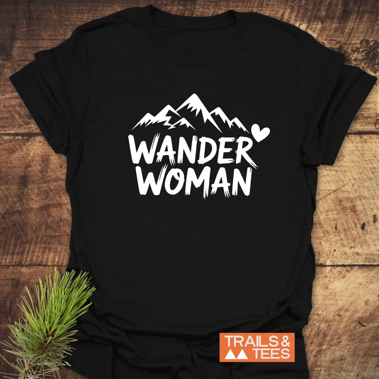 Wander Woman T-Shirt with mountain graphic, crafted from soft cotton, offering comfort and durability. Features bold “WANDER WOMAN” text, designed for outdoor enthusiasts.
