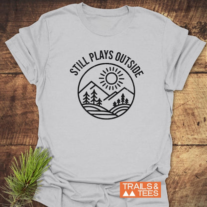 Light-gray Still Plays Outside T-shirt with black mountain emblem, crafted from soft cotton. Features durable prints, pre-shrunk fit, and eco-friendly production.