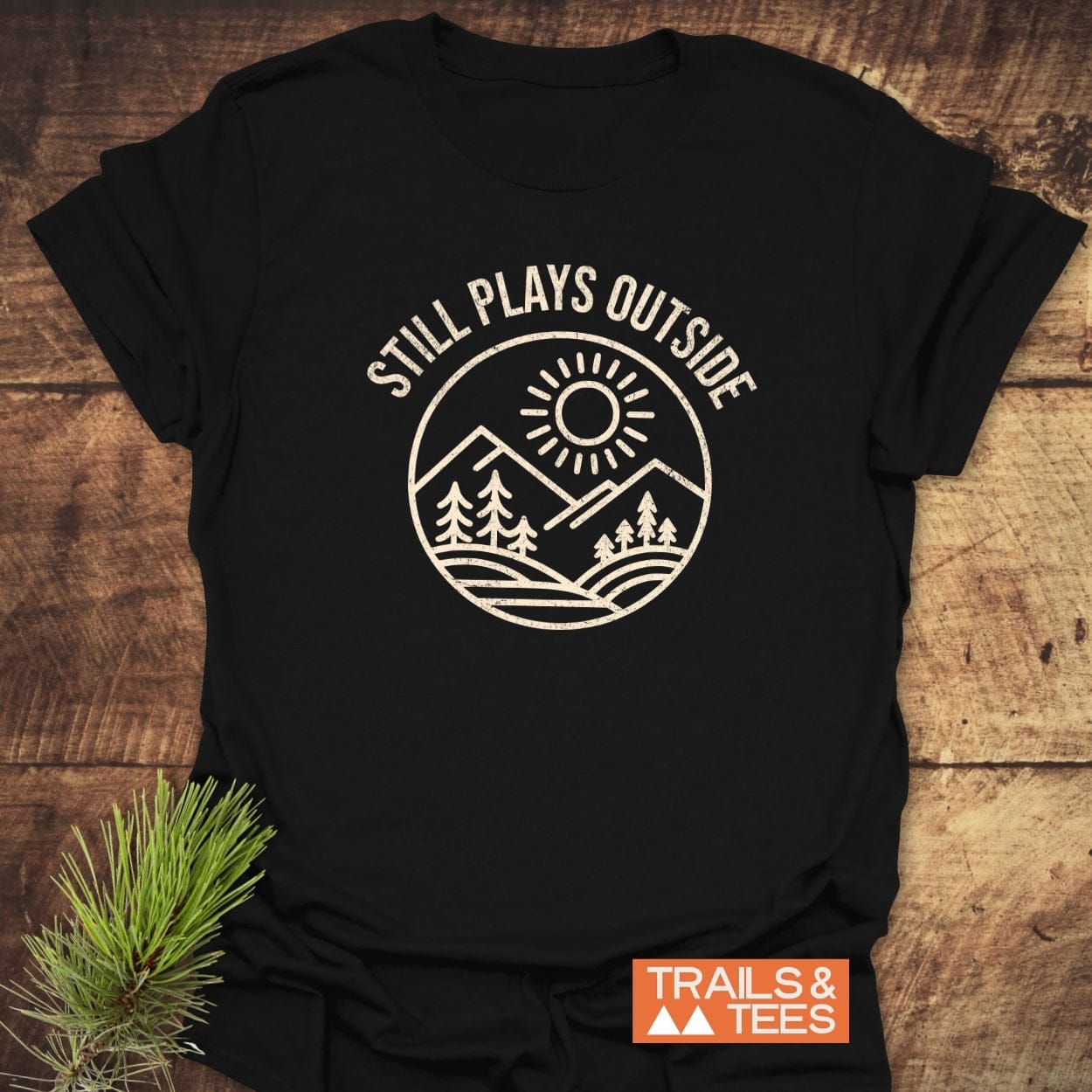 Still Plays Outside T-Shirt featuring a mountain and sun graphic, emphasizing outdoor adventure. Made from soft ring-spun cotton, it offers comfort for everyday exploration.