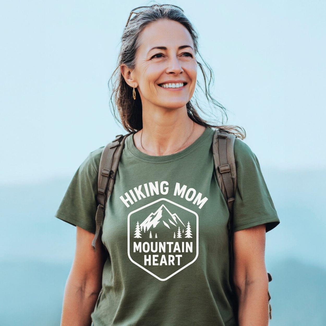 Woman hiking, wearing the Hiking Mom Mountain Heart T-Shirt with mountain graphic, showcasing its comfortable fit and durable print, perfect for outdoor enthusiasts.