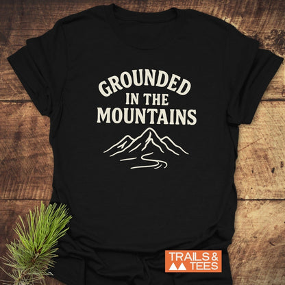 Grounded In The Mountains T-Shirt featuring off-white mountain graphic on black cotton, showcasing trail inspiration with a pine sprig accent.
