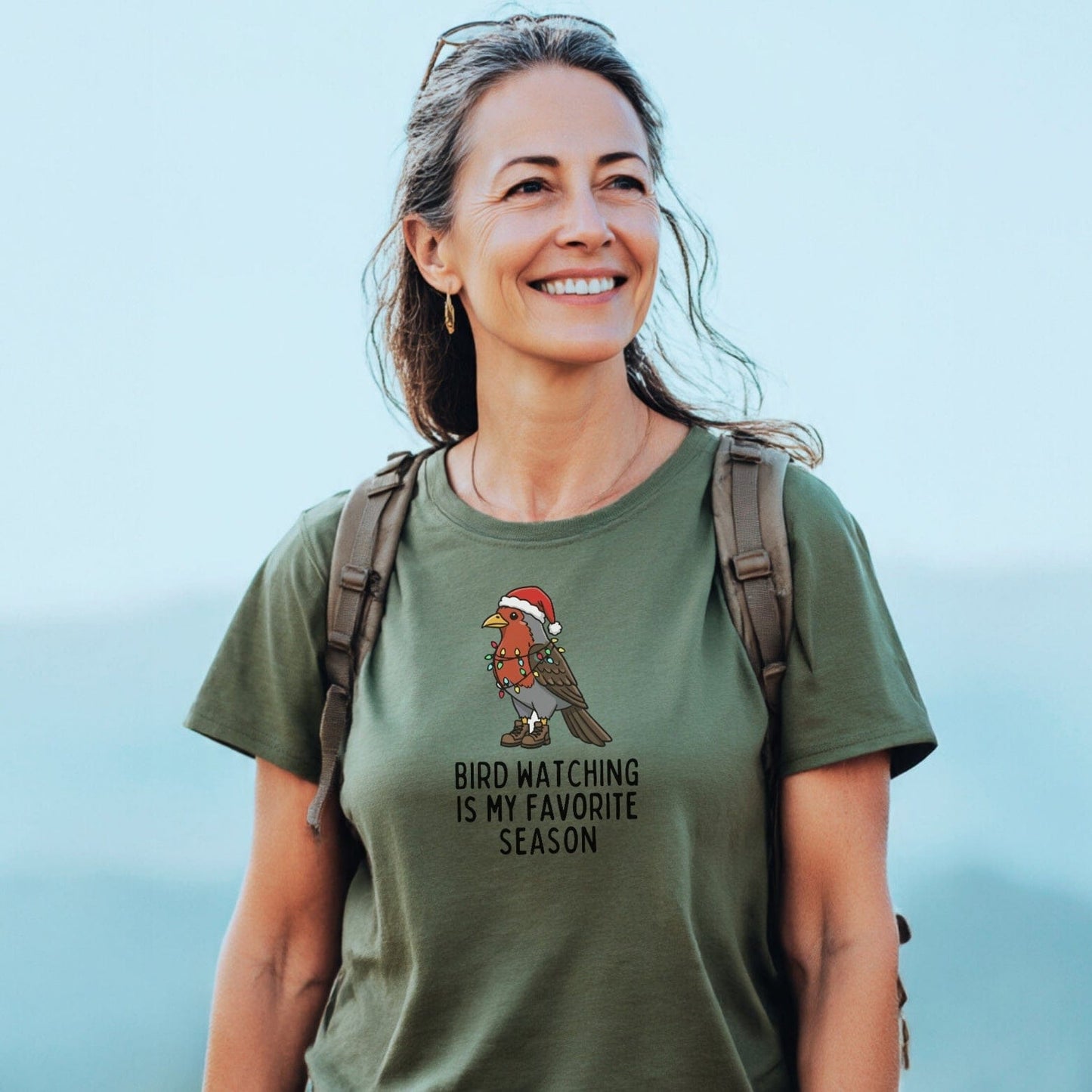Woman wearing Bird Watching Season T-Shirt with bird graphic and holiday theme, suggesting outdoor adventure; lightweight, durable cotton for comfort and lasting fit.