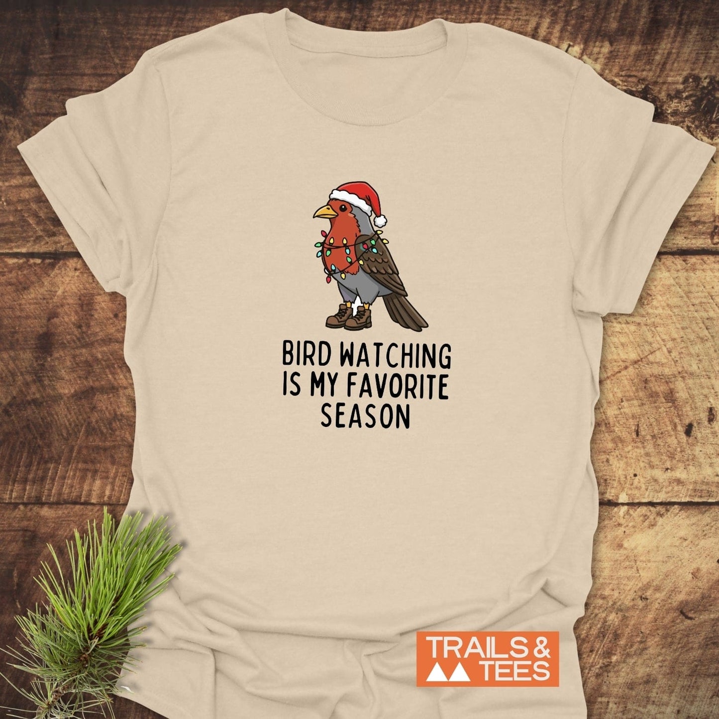 Bird Watching Season T-Shirt featuring a cartoon robin in a Santa hat, hiking boots, and Christmas lights with slogan. Soft, durable cotton, ideal for outdoor enthusiasts.