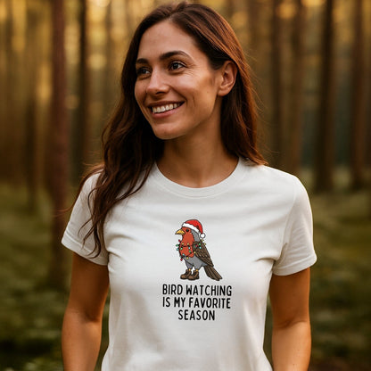 Woman in a wooded area wearing the Bird Watching Season T-Shirt with a cartoon bird in Christmas attire, showcasing outdoor adventure style and comfort.