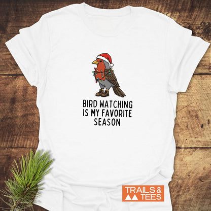 Bird Watching Season T-Shirt features a cartoon robin with Christmas lights, hiking boots, and Santa hat, sloganed for festive outdoor enthusiasts.