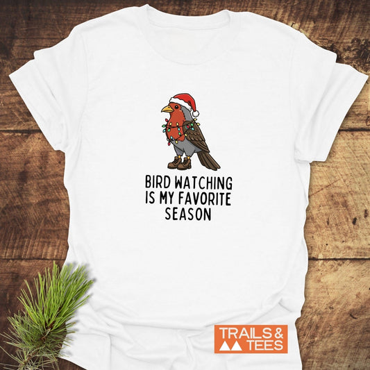 Bird Watching Season T-Shirt features a cartoon robin with Christmas lights, hiking boots, and Santa hat, sloganed for festive outdoor enthusiasts.