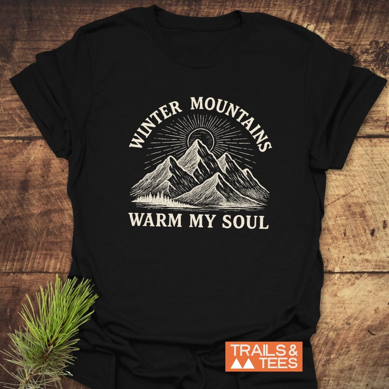 Winter Mountains T-Shirt featuring a stylized mountain range with a sunburst and the words “WARM MY SOUL,” showcasing Trails & Tees’ commitment to adventure-ready, durable, and eco-friendly design.