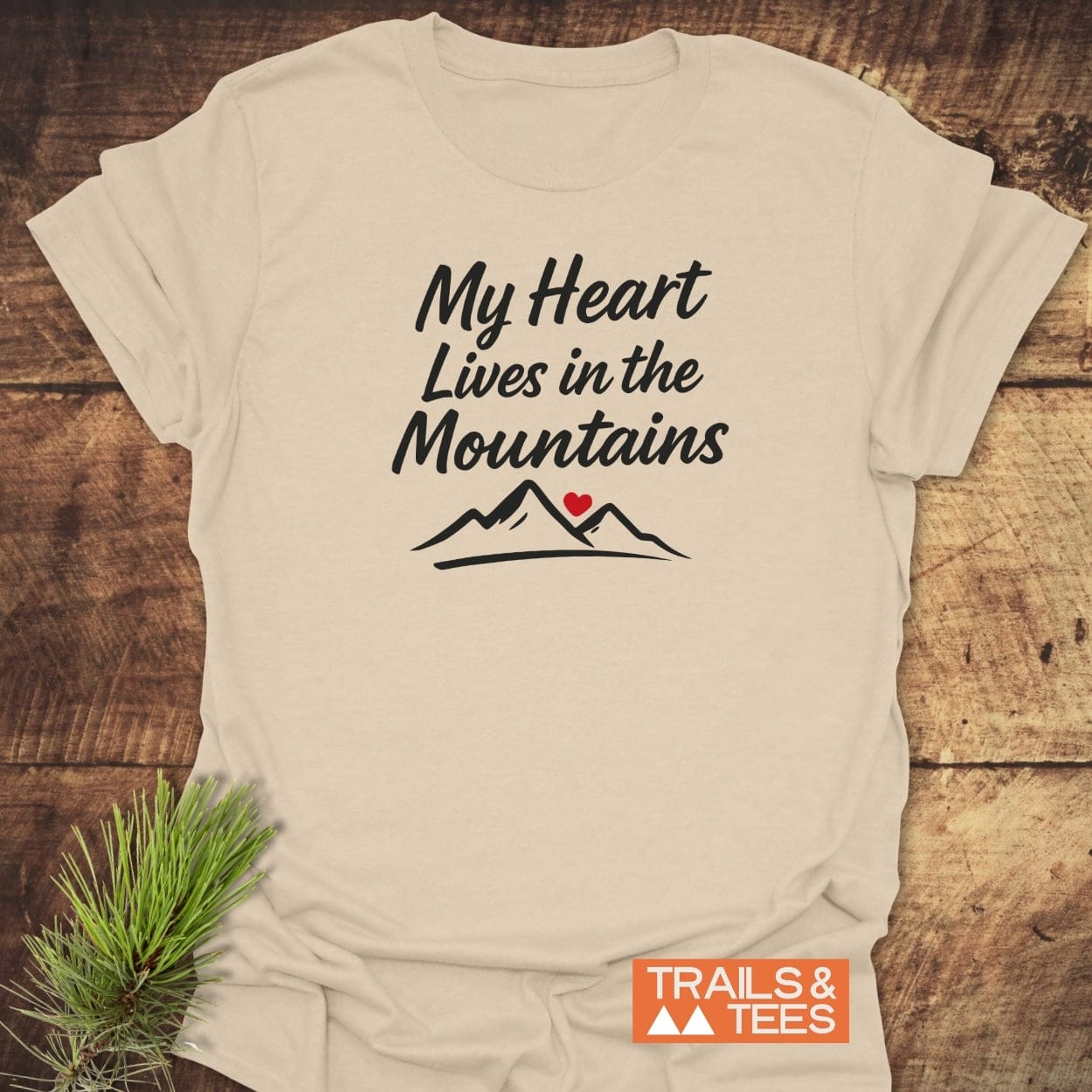 My Heart Lives In The Mountains T-Shirt features bold script and mountain peaks with a red heart. Crafted from soft cotton for comfort, it's perfect for outdoor enthusiasts and adventure seekers.