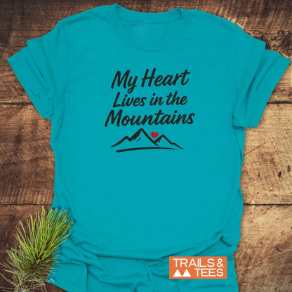 My Heart Lives In The Mountains T-Shirt featuring a hand-lettered slogan with mountains and heart design, crafted from soft cotton for comfort, perfect for outdoor enthusiasts, includes TRAILS & TEES logo.