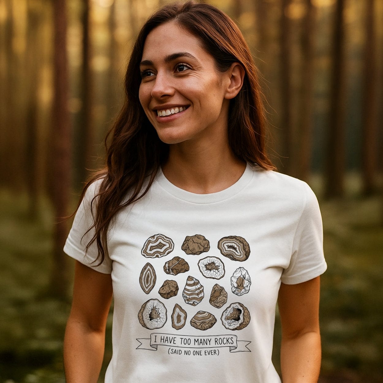 Young woman in a forest wears the I Have Too Many Rocks T-Shirt, featuring stylized rock illustrations and playful text, showcasing outdoor spirit and comfort with durable, lightweight cotton design.