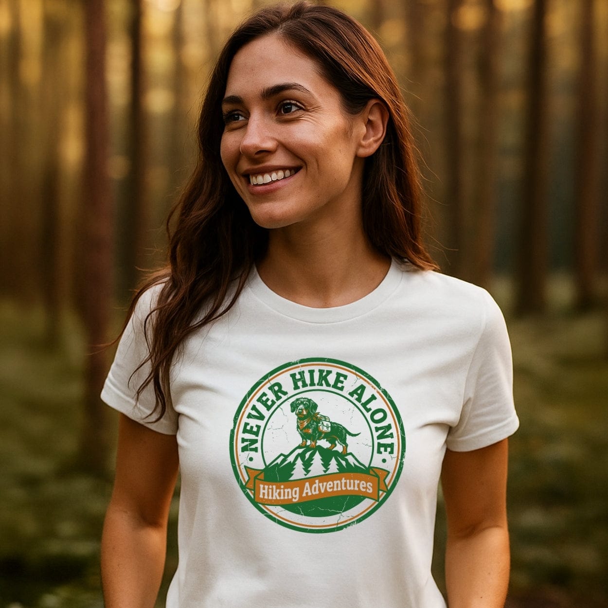 Young woman in a wooded area wearing the Never Hike Alone T-Shirt, featuring a mountain and dog badge design, symbolizing outdoor adventure and comfort with soft, ring-spun cotton.