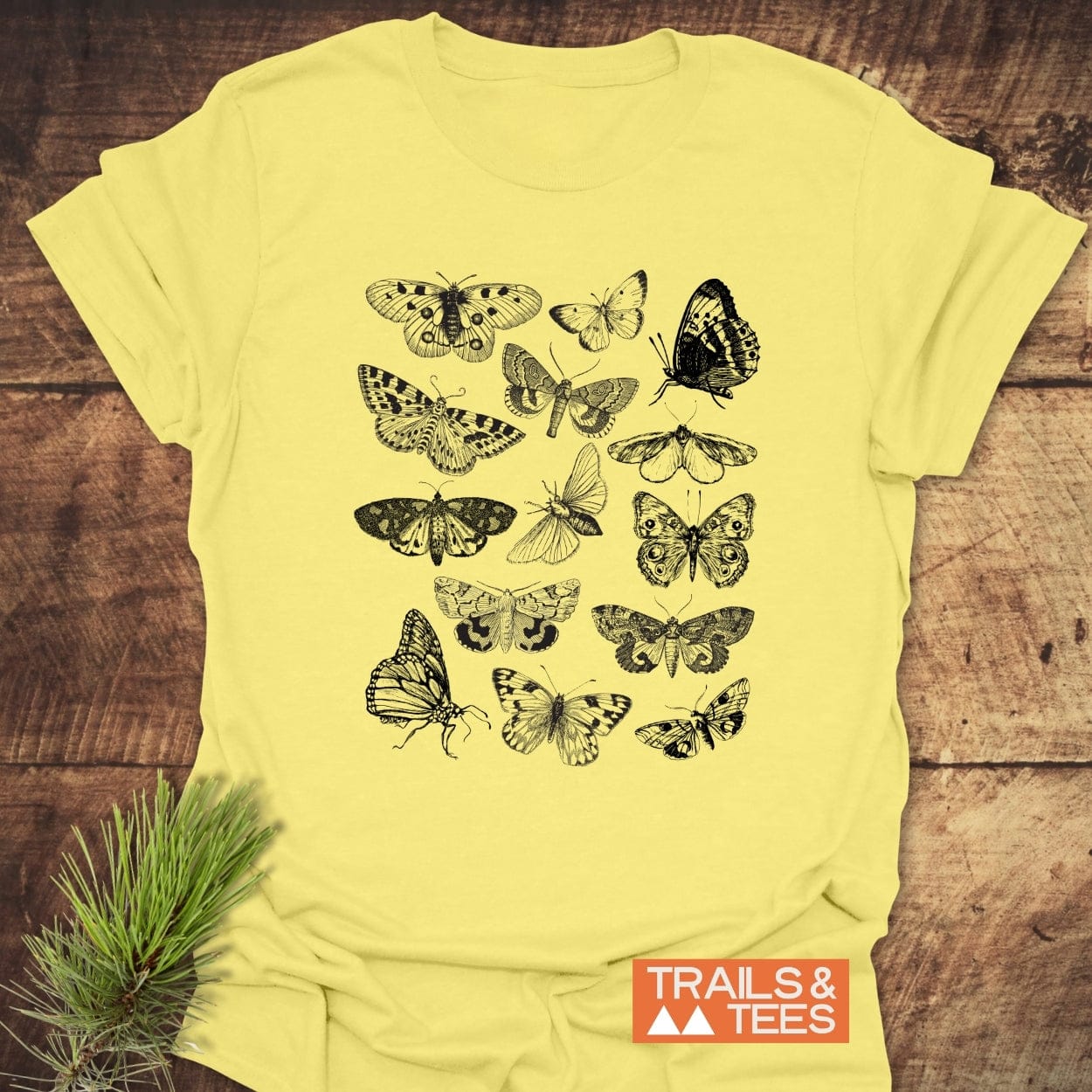 Vintage Butterfly Tattoo T-Shirt featuring a grid of intricately drawn butterflies and moths, accented by a TRAILS & TEES logo. Perfect for nature enthusiasts and adventure seekers.