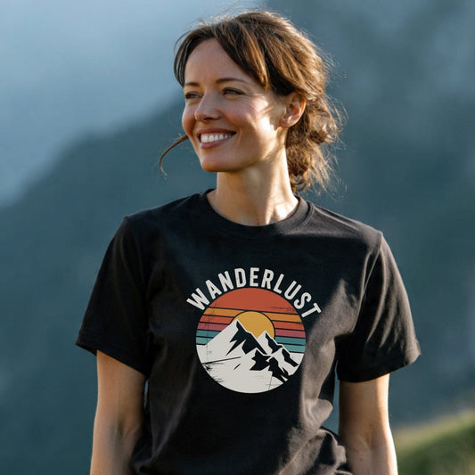 Woman in mountainous setting wearing the Wanderlust Retro T-Shirt, featuring a circular mountain graphic with a sun and WANDERLUST text, showcasing outdoor adventure style and comfort.