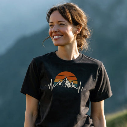 Young woman outdoors wearing the Mountain Heartbeat T-Shirt, featuring a retro sun and mountain graphic transitioning into an EKG line, symbolizing adventure and love for the outdoors.