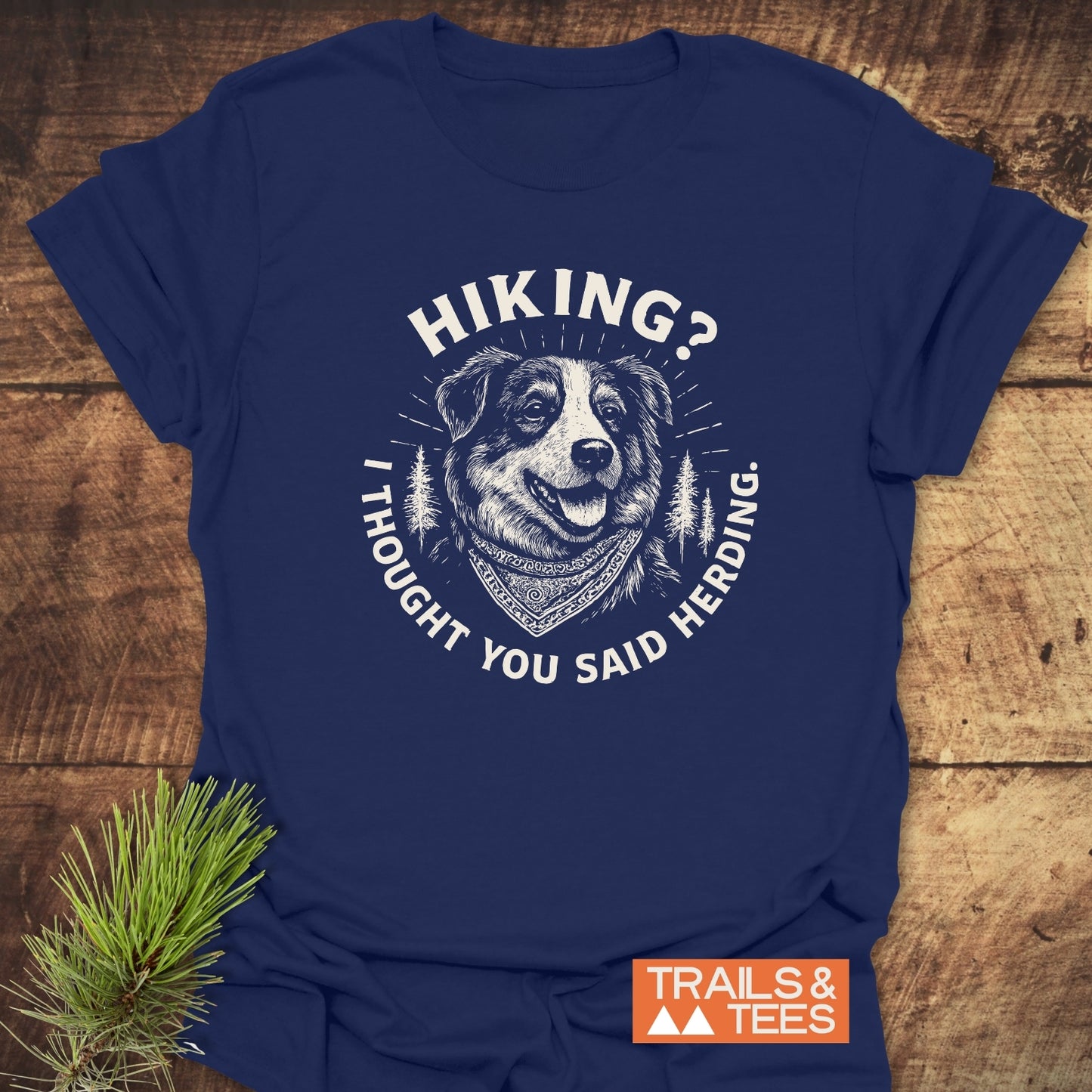 Hiking? Australian Shepherd T-Shirt on rustic wood, featuring a happy dog with pine trees and pun slogan. Includes TRAILS & TEES logo. Screen-printed, lightweight cotton, ideal for outdoor enthusiasts.