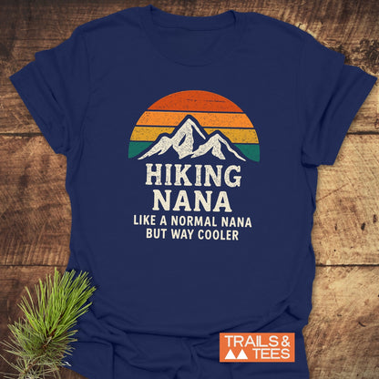 Navy T-shirt with a sunset/mountain graphic and Hiking Nana like a normal nana but way cooler slogan. Features TRAILS & TEES. logo, highlighting outdoor adventure and comfort.