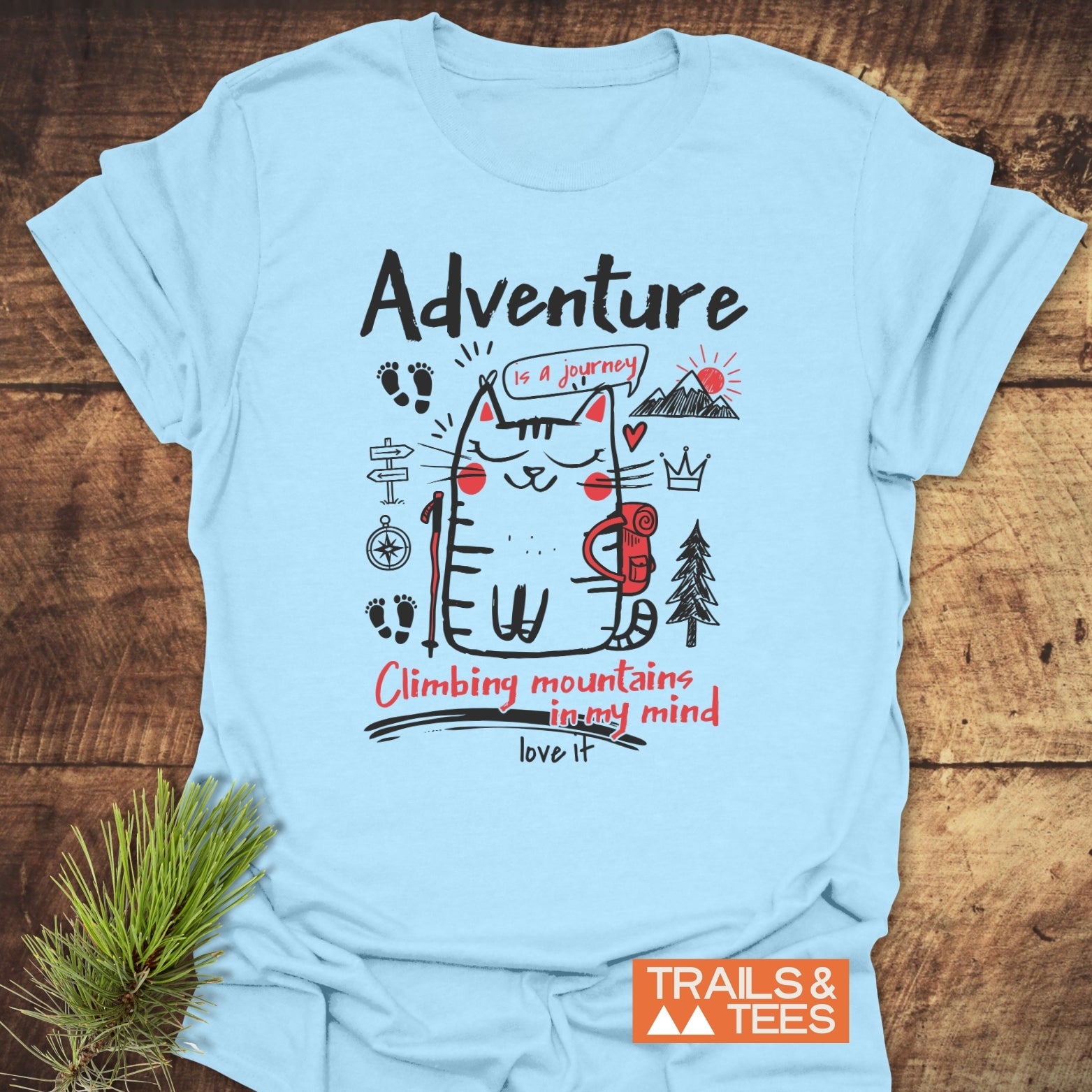 Adventure Cat Funny T-Shirt with cartoon cat hiking design, compass, trail sign, and mountain doodles. Features Adventure is a journey and Climbing mountains in my mind slogans. Durable, lightweight cotton.