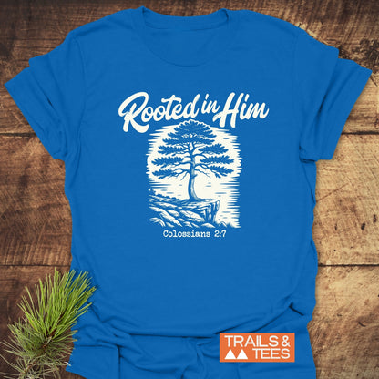 Rooted In Him Mountain T-Shirt: Features a stylized tree design with Rooted in Him text, crafted from soft ring-spun cotton, and includes an orange “TRAILS & TEES” logo.