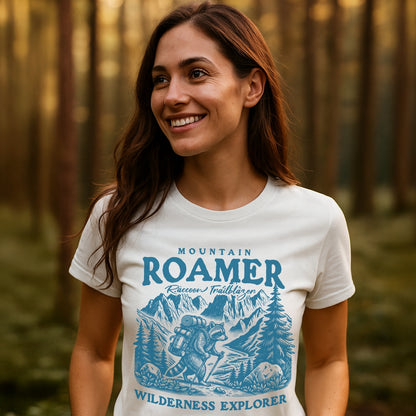 Mountain Roamer Raccoon T-Shirt featuring a playful raccoon graphic with hiking gear amidst mountains and trees, epitomizing outdoor spirit. Ideal for adventure enthusiasts seeking comfort and style in nature-themed apparel.