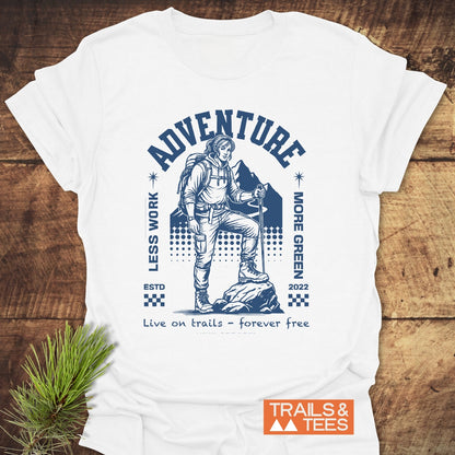 Adventure Retro T-Shirt with a navy graphic of a hiker on a rocky outcrop, mountain backdrop, and phrases “LESS WORK, MORE GREEN.” Features “ADVENTURE” and “Live on trails – forever free” text.