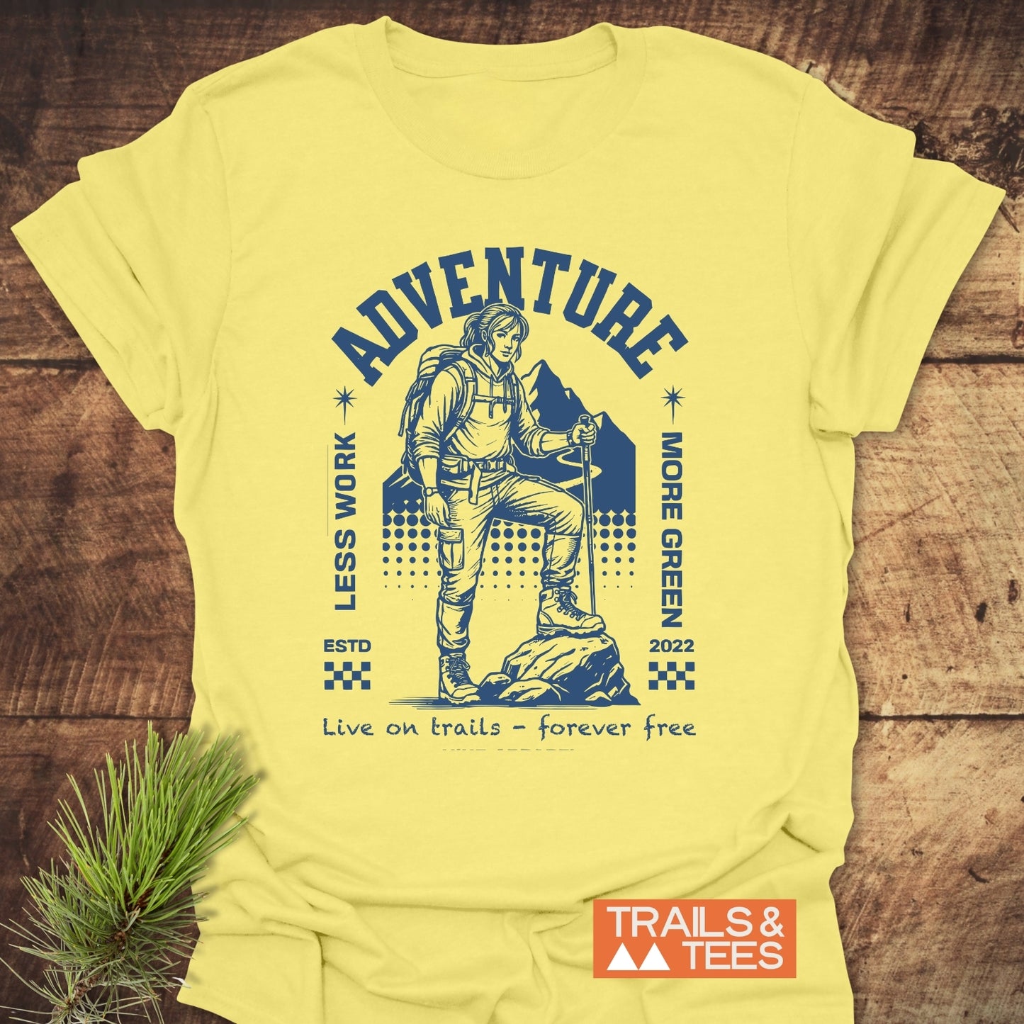 Adventure Retro T-Shirt featuring a blue graphic of a hiker and mountains, adorned with the phrases “LESS WORK, MORE GREEN,” “ADVENTURE,” and “Live on trails – forever free.”